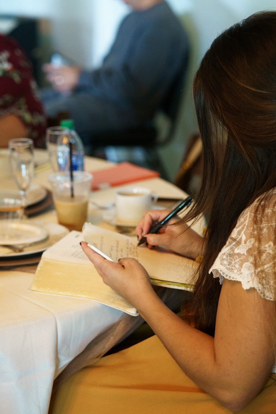 A woman taking notes in her Bible at a set table