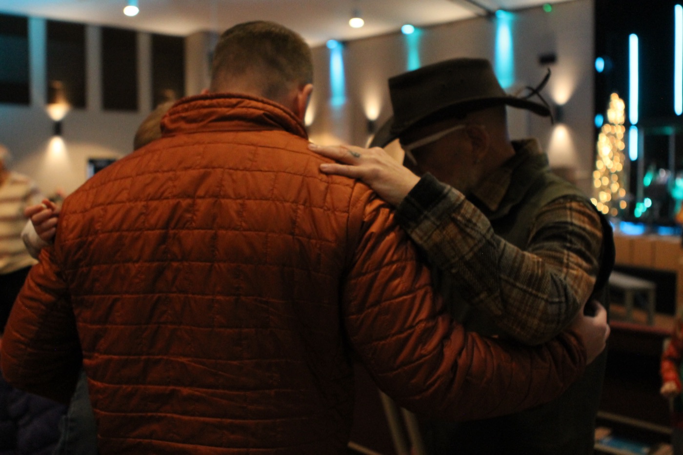 Two men praying with their arms around each other