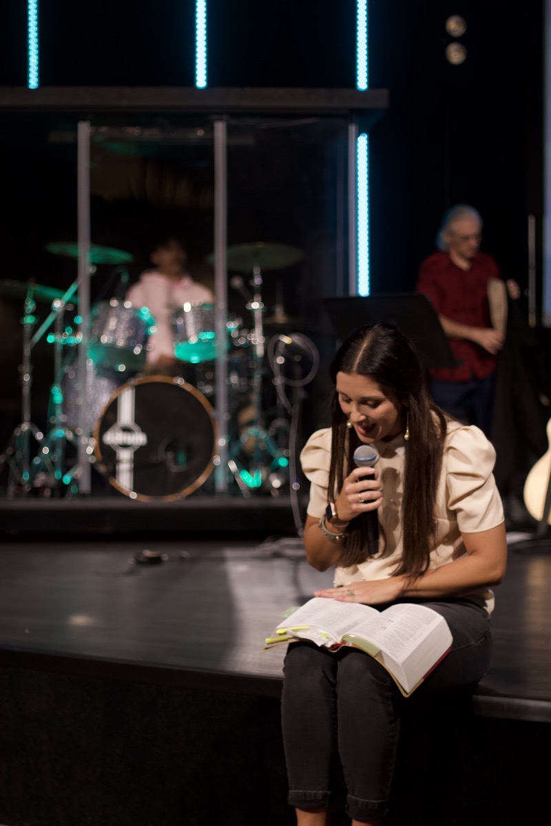 Rachel sitting on a stage step with an open, tabbed Bible on her lap