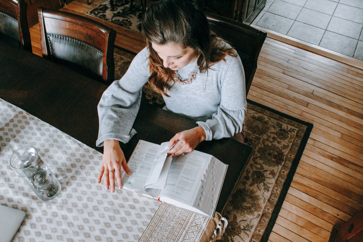 A woman reading her Bible at her dining table